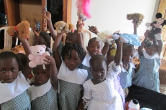 Children at orphanage in Uganda hold up their toys